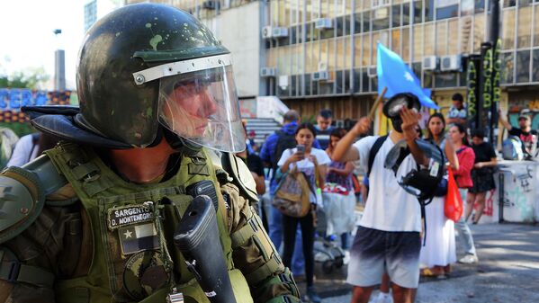 Carabinero perteneciente a Fuerzas Especiales observa a manifestantes. Metro Universidad de Chile, Paseo Ahumada esquina Alameda. - Sputnik Mundo