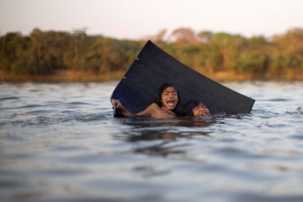 El ritual tiene lugar en el Parque Nacional de Xingu.En la foto: unos niños juegan en el río Xingu durante el ritual de quarup. - Sputnik Mundo