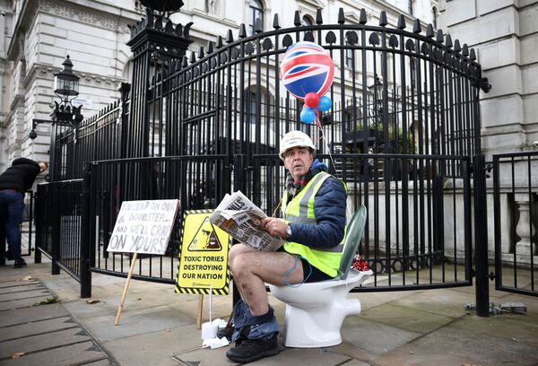 El activista Steve Bray, sentado en un inodoro frente a la residencia del primer ministro británico para protestar contra la Ley Medioambiental que permite a las compañías verter las aguas residuales a los ríos y mares del Reino Unido. - Sputnik Mundo