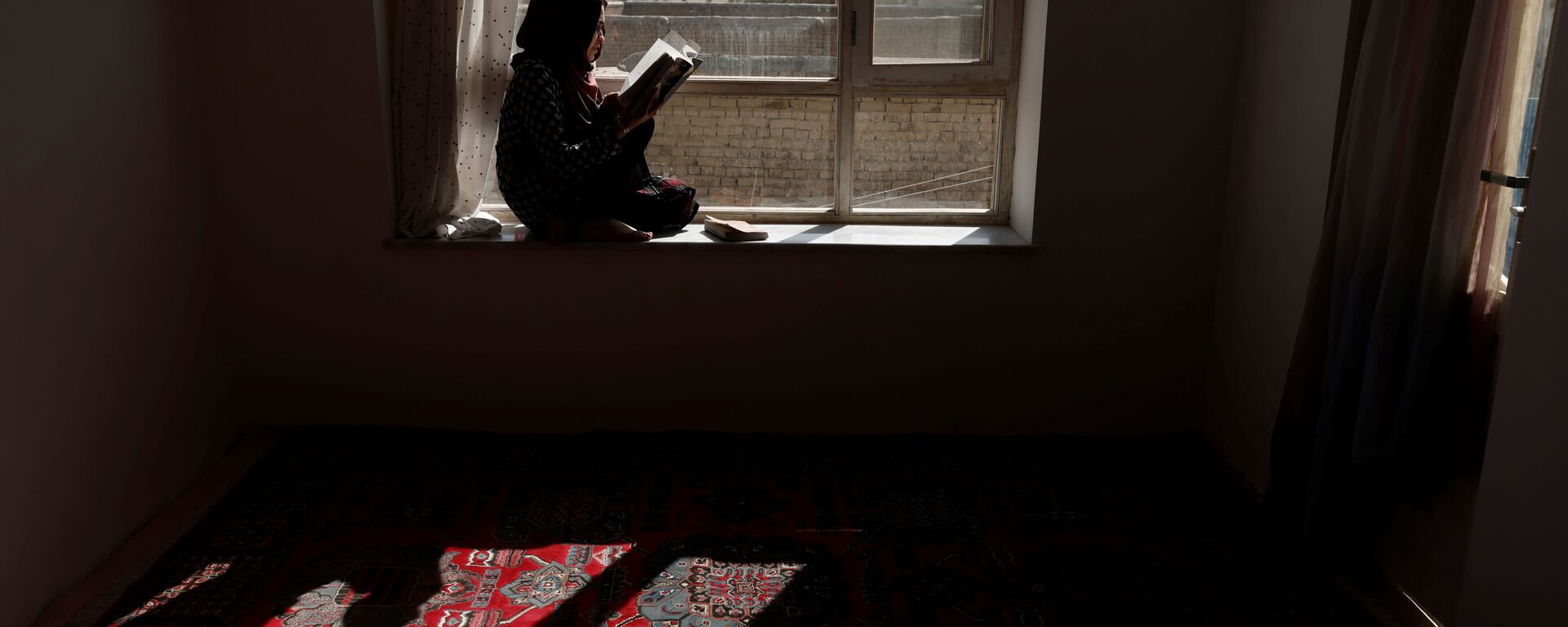 20-летняя студентка Хава читает книгу на подоконнике своего дома в Кабуле, Афганистан - Sputnik Mundo, 1920, 06.11.2021