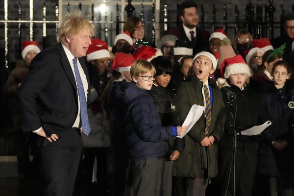 El primer ministro Boris Johnson y miembros del coro de niños en Downing Street durante la ceremonia de encendido del árbol de Navidad, 1 de diciembre de 2021. - Sputnik Mundo