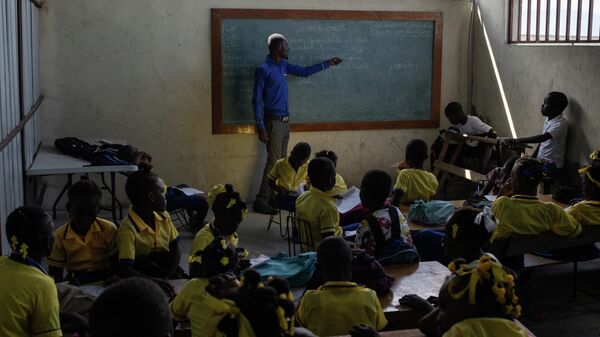 Un maestro imparte clases para los alumnos en la Escuela St Mary de Famille Kizito ubicada en Cite Soleil, Port-au-Prince, Haití  - Sputnik Mundo