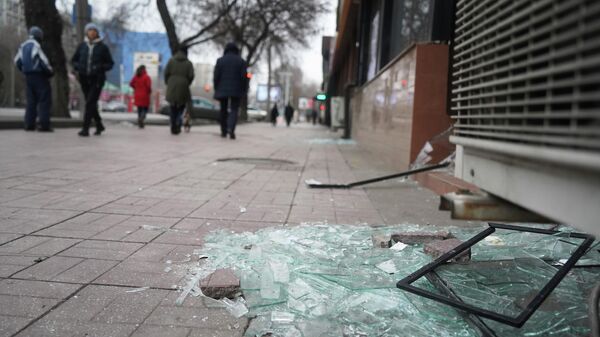 La gente pasaa por delante de una tienda con los escaparates rotos durante los enfrentamientos en Almaty, Kazajistán - Sputnik Mundo