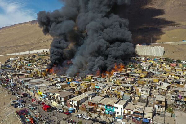 Varias casas arden en llamas durante un incendio masivo en un barrio de Iquique, en Chile. - Sputnik Mundo