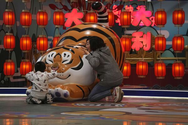 Una mujer y su hijo juegan cerca de un tigre decorativo, el símbolo del año 2022, en un centro comercial de Pekín, en China. - Sputnik Mundo