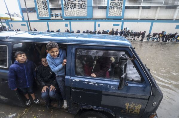Varios estudiantes palestinos esperan su turno para cruzar una calle inundada mientras van a su escuela en la ciudad de Gaza. - Sputnik Mundo