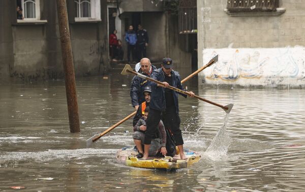 Las autoridades de Gaza culpan al Gobierno israelí por las inundaciones. Alegan que el lado israelí inundó las regiones orientales de la Franja de Gaza al abrir una presa para desviar el exceso de agua de lluvia del arroyo Wadi Gaza.En la foto: unos bomberos evacúan a las personas del campo de refugiados inundado de Jabalia, en el norte de la Franja de Gaza. - Sputnik Mundo