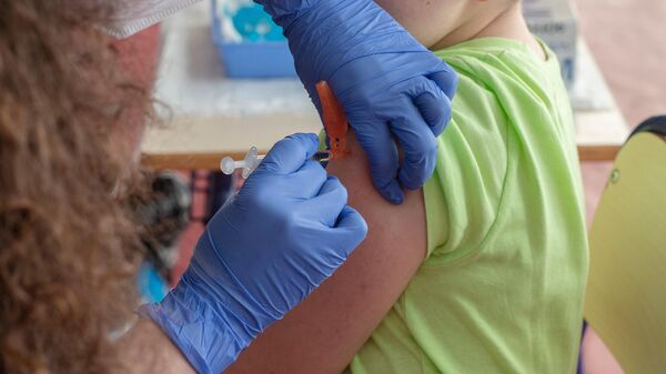 Un niño recibe la vacuna contra el COVID-19 - Sputnik Mundo