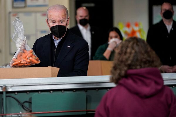 El presidente de Estados Unidos, Joe Biden, pone una bolsa de zanahorias en una caja de Philabundance, una organización de ayuda contra el hambre en Filadelfia. - Sputnik Mundo