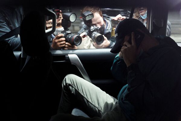 Varios corresponsales fotografían a un hombre no identificado saliendo del aparcamiento del despacho del abogado del tenista serbio Novak Djokovic en Melbourne (Australia), acompañado de coches de policía. - Sputnik Mundo
