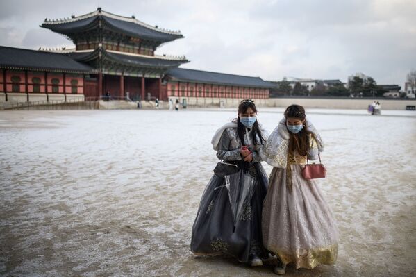 Dos mujeres con trajes tradicionales cerca del recinto del Palacio de Gyeongbokgung tras una nevada en Seúl, Corea del Sur. - Sputnik Mundo