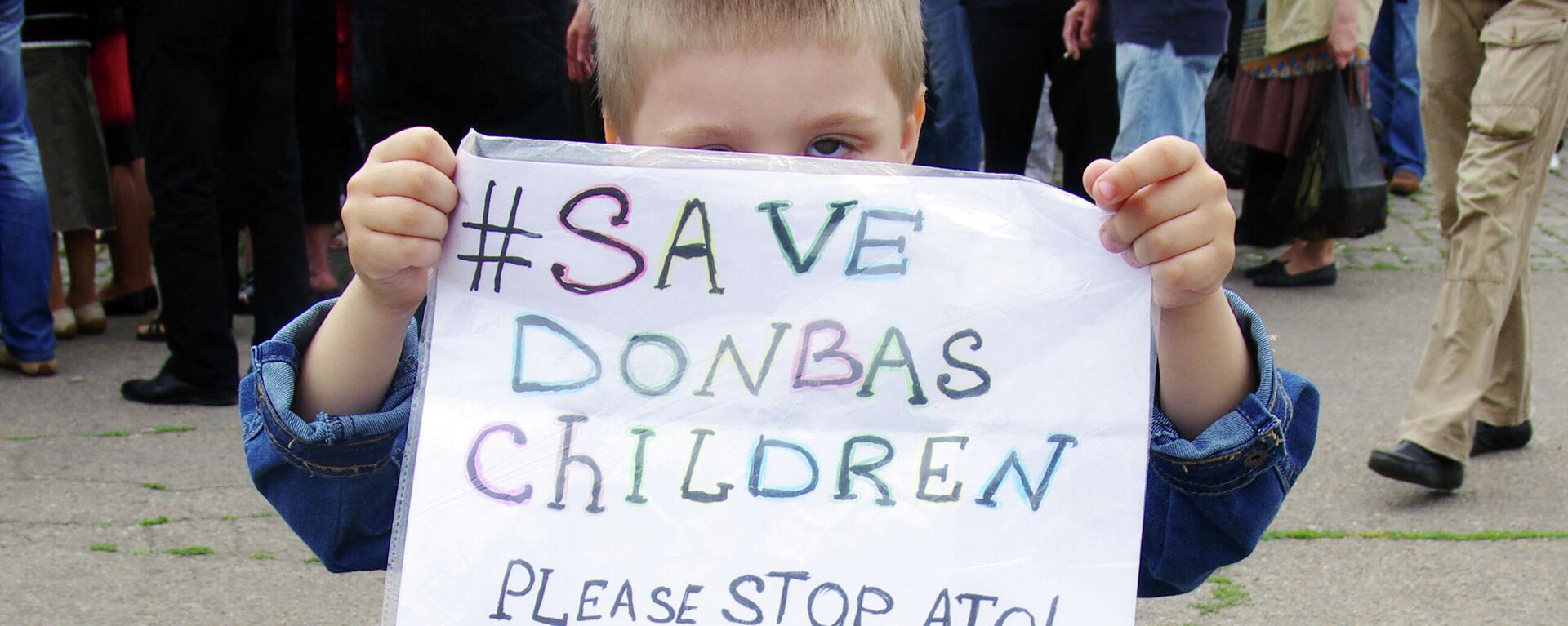 Un niño en Donbás muestra el póster Save Donbas children. Please stop ATO! - Sputnik Mundo, 1920, 21.01.2022