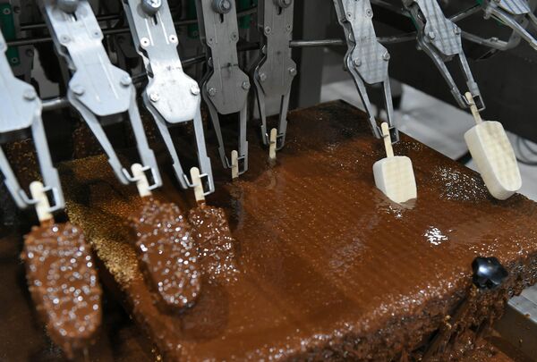 Así se encontró el método correcto. Una briqueta de helado se divide en 16 trozos. Cada pieza está recubierta de una mezcla de chocolate con leche fundido y manteca de cacao. El glaseado se seca muy rápidamente, en unos 10 segundos. El &quot;pastel&quot; de chocolate con el helado en su interior se envía a la nevera.En la foto: el proceso de fabricación del helado Eskimo Pie. - Sputnik Mundo