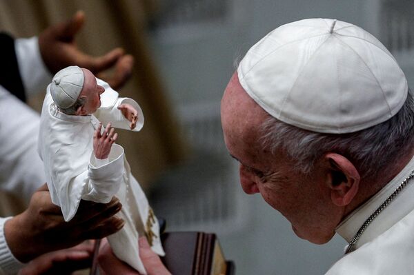 El papa Francisco observa su escultura en miniatura en manos de un feligrés durante su audiencia general semanal en el Vaticano. - Sputnik Mundo