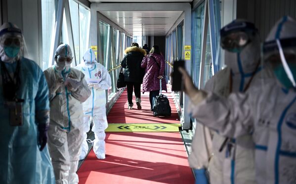 Personal médico con trajes de protección en una rampa telescópica del aeropuerto de Pekín (China). - Sputnik Mundo