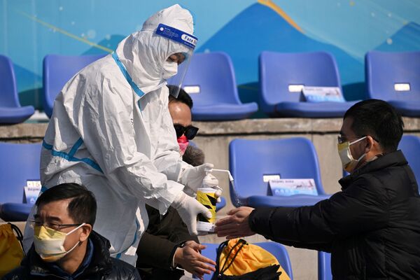 Un miembro del personal trata las manos de los espectadores con una solución desinfectante en el centro de competición de big air en el Parque de Nieve de Shougan, en Pekín. - Sputnik Mundo