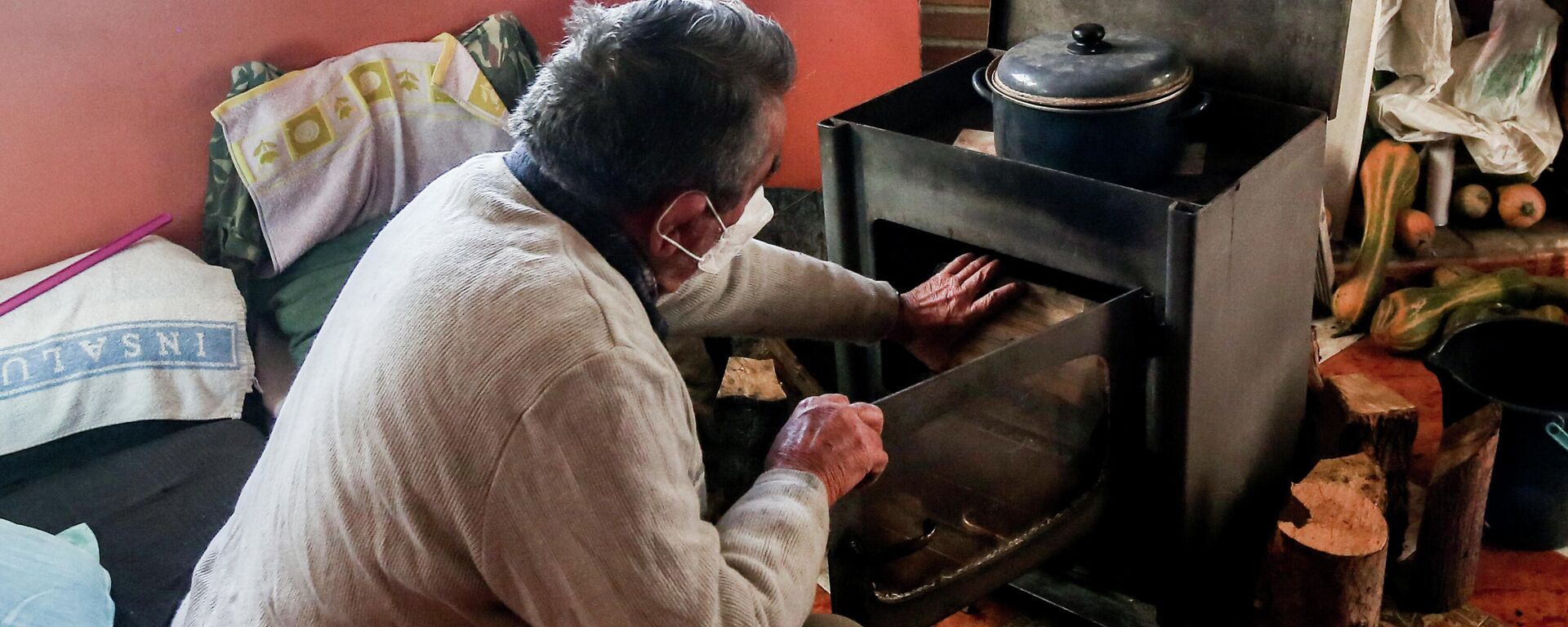 Un hombre calienta una estufa en su vivienda del Sector 6 de la Cañada Real. Madrid, 31 de diciembre de 2021. - Sputnik Mundo, 1920, 16.02.2022