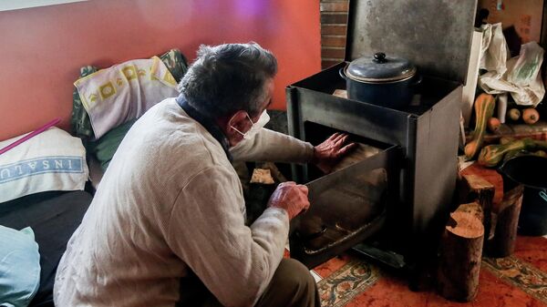 Un hombre calienta una estufa en su vivienda del Sector 6 de la Cañada Real. Madrid, 31 de diciembre de 2021. - Sputnik Mundo
