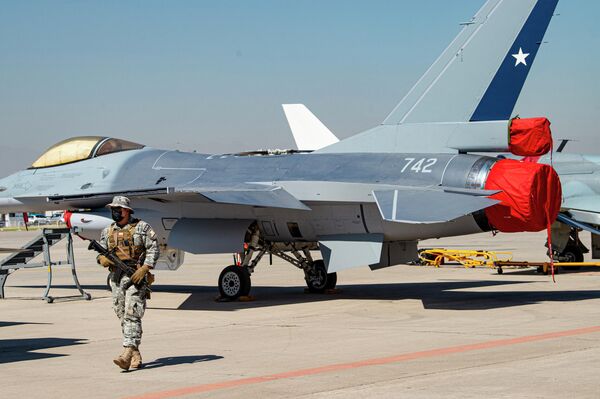 Un militar chileno al lado de un caza F16 de la Fuerza Aérea de Chile durante la FIDAE 2022. - Sputnik Mundo