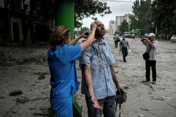 Durante los bombardeos, los médicos salieron a las calles para empezar a prestar atención médica de urgencia de inmediato. En la foto, un médico atiende a un herido durante el bombardeo ucraniano en la ciudad de Lugansk en el año 2014. - Sputnik Mundo