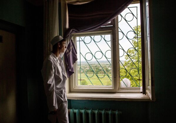 A menudo, el frente de la guerra se acercaba al hospital, pero los médicos no interrumpían su trabajo hasta el último minuto. Año 2014: en el pueblo de Semiónovka, de la región de Donetsk, un médico de un hospital bombardeado por el Ejército ucraniano mira hacia las posiciones ucranianas. - Sputnik Mundo