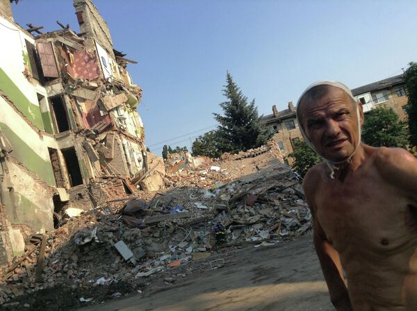 Julio de 2014. La ciudad de Snézhnoie en la región de Donetsk. Víktor Stepanenko, de 70 años, frente a su casa destruida por un misil ucraniano. Su esposa y otras 11 personas murieron en la explosión. El propio hombre sobrevivió milagrosamente tras caer desde el cuarto piso. Se salvó al caer en un pino. - Sputnik Mundo