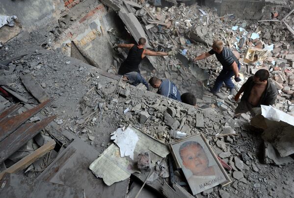 Julio de 2014. La ciudad de Snézhnoie. Rescatistas y vecinos retiran los escombros de una casa tras un ataque aéreo del Ejército ucraniano. - Sputnik Mundo