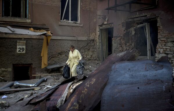 Julio de 2014. Una mujer en el patio de una casa destruida por los bombardeos en Lugansk. - Sputnik Mundo