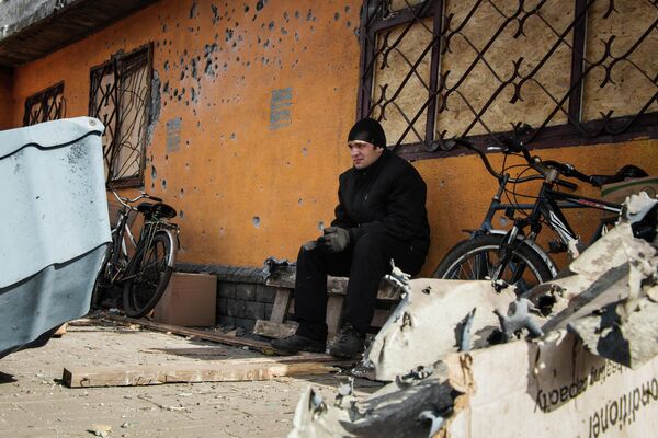 Febrero de 2015. Un residente del pueblo de Debáltsevo, en la región de Donetsk, sentado frente a un edificio dañado por los bombardeos de las Fuerzas ucranianas. - Sputnik Mundo
