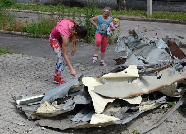 Junio de 2017. Unos niños miran el revestimiento de un edificio dañado por los bombardeos en Donetsk. - Sputnik Mundo