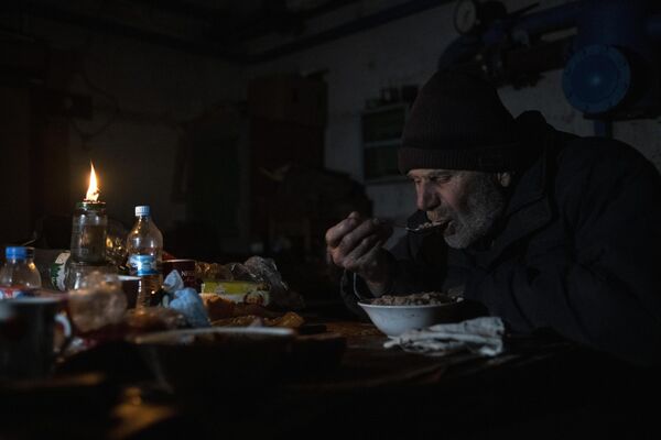En sótanos oscuros y fríos, los ancianos esperaban el bombardeo de sus casas. En la foto: un hombre cena en el sótano de una casa en la ciudad de Rubezhnoe, región de Lugansk. - Sputnik Mundo