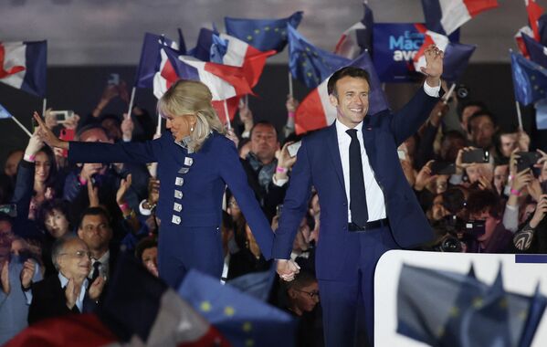 El presidente de Francia y candidato del partido La República en Marcha (LREM), Emmanuel Macron, y su esposa Brigitte celebran tras su victoria en las elecciones presidenciales en el Campo de Marte, en París, el 24 de abril de 2022. - Sputnik Mundo