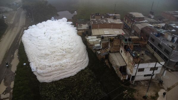Una vista aérea muestra cómo la espuma formada en un río contaminado invade el barrio Los Puentes, en Mosquera, al oeste de Bogotá. 26 de abril de 2022. - Sputnik Mundo