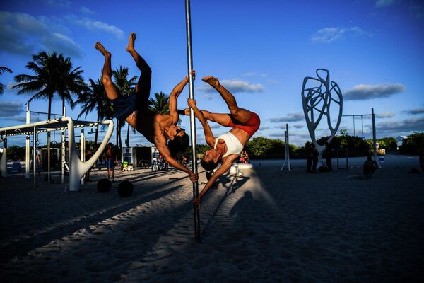 Dos personas hacen acrobacias con pértiga sobre la arena de Miami Beach, en Florida. - Sputnik Mundo