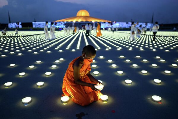 Un joven monje budista arregla una luz LED durante las celebraciones del Día de la Tierra realizadas en el templo budista Wat Dhammakaya en la provincia de Pathum Thani, al norte de Bangkok, Tailandia. - Sputnik Mundo