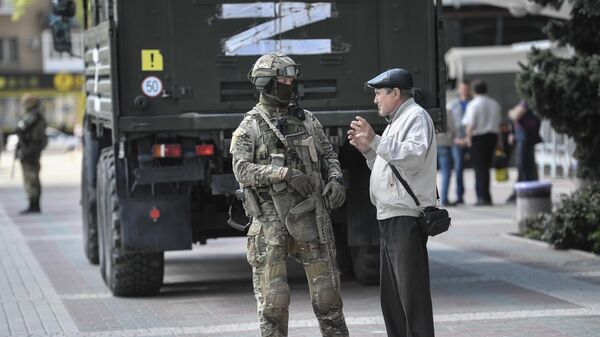 Un hombre está hablando con un militar ruso en Melitópol durante la operación especial militar de Rusia en Ucrania - Sputnik Mundo