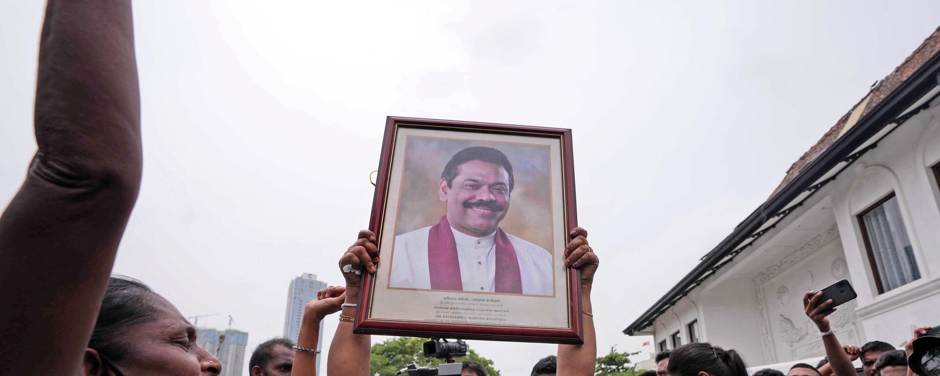 Los Partidarios del gobierno de Sri Lanka sostienen un retrato del ex primer ministro Mahinda Rajapaksa - Sputnik Mundo, 1920, 11.05.2022
