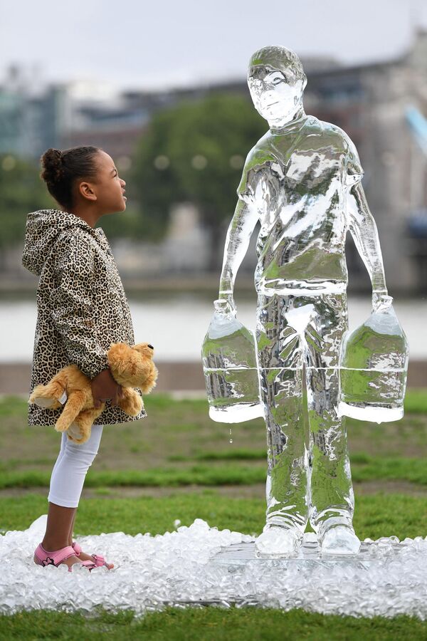 Niños ante la escultura de hielo que representa a las personas recogiendo agua creada por la organización benéfica Water Aid para concientizar sobre la falta de agua potable en algunas regiones de nuestro planeta, 15 de septiembre de 2021. - Sputnik Mundo