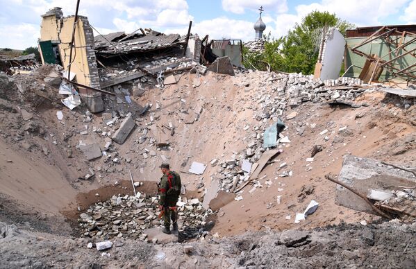 Un militar de la República Popular de Lugansk se para sobre un socavón que resultó de un ataque aéreo de las Fuerzas Armadas de Ucrania en el pueblo de Yatskovka, en el territorio del distrito Liman de la República Popular de Donetsk. - Sputnik Mundo