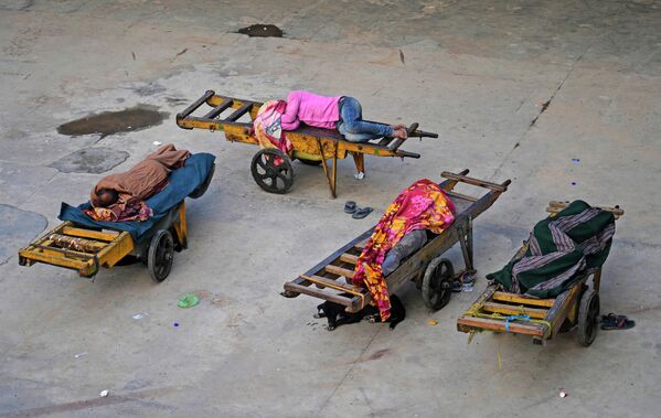 Los maleteros duermen en sus carros cerca de una estación de tren en Nueva Deli, India. - Sputnik Mundo