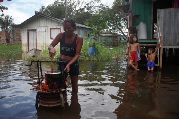 Una residente de Iranduba, estado de Amazonas, Brasil, prepara la comida para su familia en el patio de una casa inundada debido a la crecida del Río Negro.
 - Sputnik Mundo