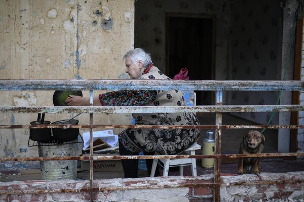 Una mujer prepara la comida en el balcón de un edificio de apartamentos en Mariúpol, en la República Popular de Donetsk. - Sputnik Mundo