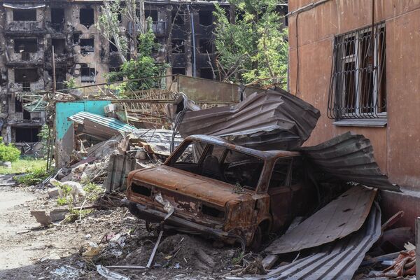 Una de las principales tareas ahora es despejar los escombros de las zonas residenciales.En la foto: un coche dañado en una calle de Mariúpo - Sputnik Mundo