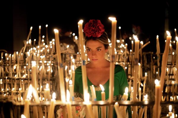 Una peregrina enciende una vela en la ermita del Rocío, en Andalucía, donde se celebra anualmente la famosa Romería de El Rocío, en la que se venera a la Virgen del Rocío. - Sputnik Mundo