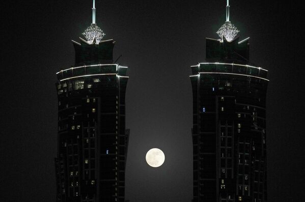La luna de fresa se levanta entre dos rascacielos en Dubái, EAU. - Sputnik Mundo