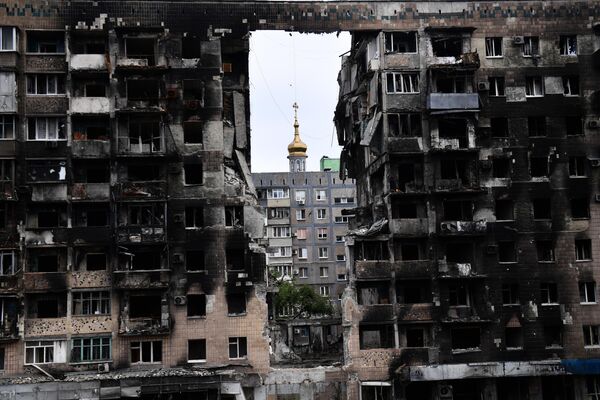 Un edificio residencial destruido en la avenida de Metallurg de Mariúpol, en la República Popular de Donetsk. En el fondo está la iglesia ortodoxa de la Intercesión. - Sputnik Mundo