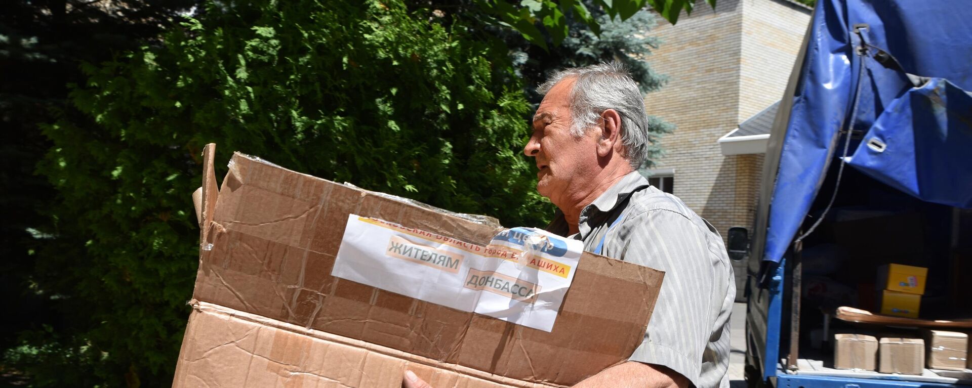 Un hombre con una caja de ayuda humanitaria para Donbás - Sputnik Mundo, 1920, 07.07.2022