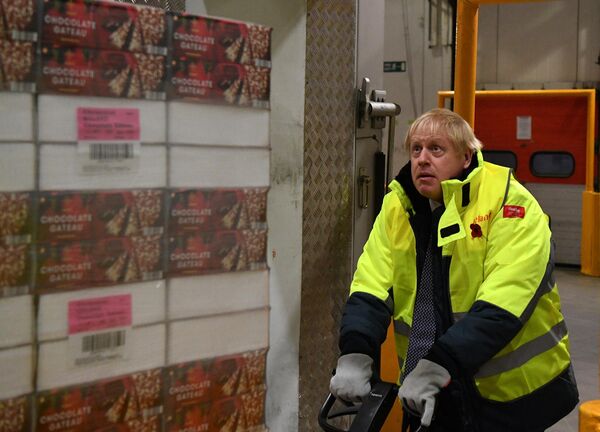 El primer ministro Boris Johnson mueve un palé de pasteles de chocolate en un almacén a 25 grados bajo cero durante una visita a la sede de Iceland Foods en Gales como parte de la campaña previa a las elecciones parlamentarias, en noviembre de 2019. - Sputnik Mundo