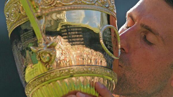 El multipremiado tenista Novak Djokovic con su trofeo en Campeonato de Wimbledon 2022 - Sputnik Mundo