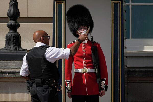 Un policía da agua a un guardia de servicio en el Palacio de Buckingham, en Londres, mientras las temperaturas suben a 40 grados.
 - Sputnik Mundo